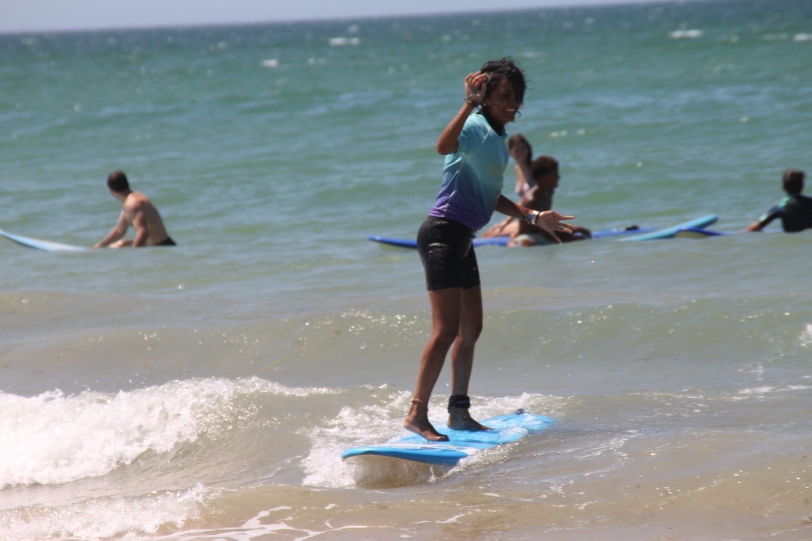 Alumna surfeando de pie en una ola en Zahara de los Atunes