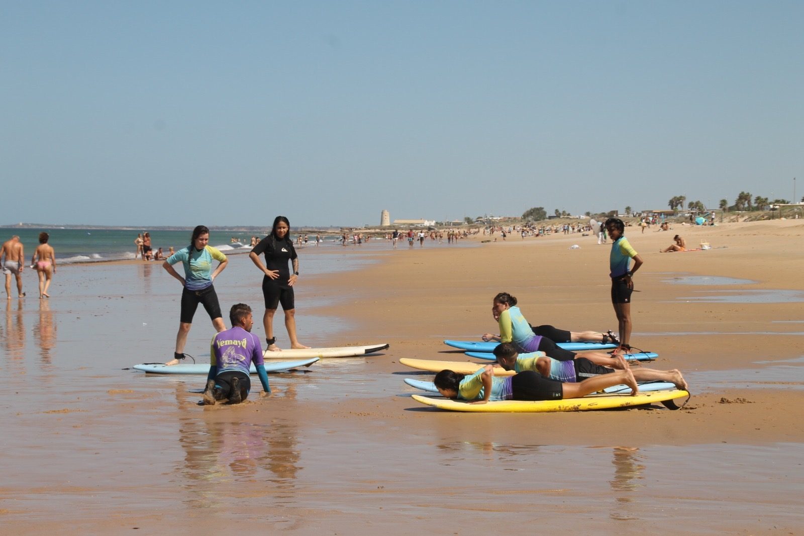 Alumnas caminando con tablas de surf al atardecer en Zahara de los Atunes